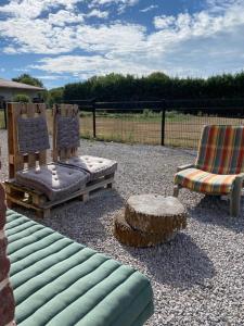 eine Terrasse mit zwei Stühlen, einem Sofa und einem Stumpf in der Unterkunft La Grange du marais de Sailly-Bray in Noyelles-sur-Mer