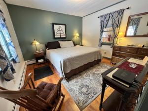 a bedroom with a bed and a table and a desk at Alamoosook Lakeside Inn Orland in Orland