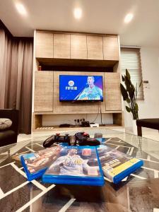 a living room with a glass table and a tv at Cozy Family Escape by StayCo - Pool, KTV, Outdoor Cinema & JACUZZI - Just 2 mins to Beach in Batu Ferringhi