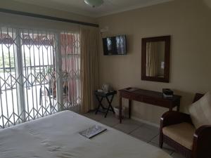 1 dormitorio con cama, mesa y espejo en Ingwe Manor Guesthouse en Margate