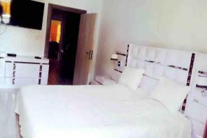 a bedroom with a white bed and a television at Terranga et douceur aux almadies in Dakar