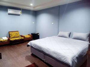 1 dormitorio con 1 cama grande y 2 sillas en เฮือนพรนาคา โฮมสเตย์, en Ban Don Klang