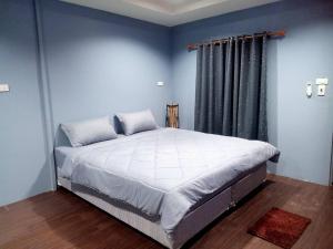 a bedroom with a large bed with blue walls at เฮือนพรนาคา โฮมสเตย์ in Ban Don Klang