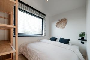 um quarto com uma cama branca e uma janela em B-LESS em Blankenberge
