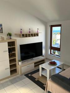 a living room with a television and a table at Apartmani Porat Malinska in Malinska