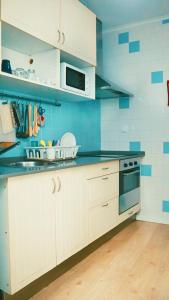 a kitchen with white cabinets and a blue wall at 70's Hostel in Ericeira