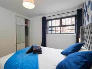 Un dormitorio con una cama con almohadas azules y una ventana en West Point, Derby city centre, en Derby