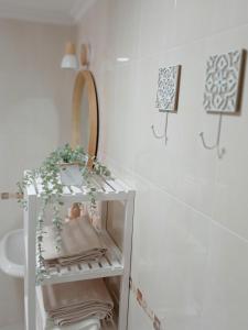een witte badkamer met een plank met handdoeken en een spiegel bij Primera linea de Playa a 10 min Estepona in San Luis de Sabinillas