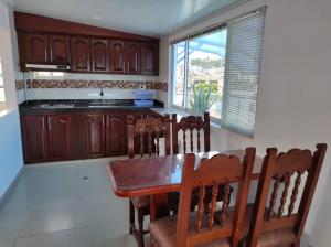 una cocina con armarios de madera, mesa y sillas en Apartamento en el Corazón de Paipa., en Paipa