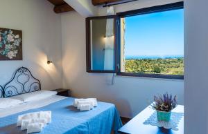 a bedroom with a bed and a large window at Casale Ginisara in Castellammare del Golfo