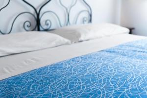 a bed with blue and white sheets and pillows at Casale Ginisara in Castellammare del Golfo