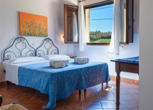 a bedroom with a bed and a table and a window at Casale Ginisara in Castellammare del Golfo