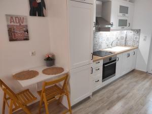 a kitchen with white cabinets and a table and chairs at ANGEL STUDIOS VRACHOS BEACH PREVEZA in Vrachos