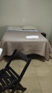 Una cama en una habitación con una silla al lado en Hotel & Restaurante Frezza, en Francisco Beltrão