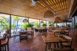 un restaurante con mesas y sillas de madera y muchas ventanas en Blue Emerald Beachfront Blessing en Willemstad