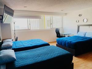 1 dormitorio con 2 camas azules y mesa en Allegro Polanco, en Ciudad de México