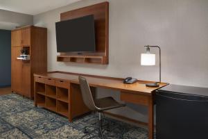 a hotel room with a desk with a monitor and a chair at Four Points by Sheraton Hotel & Conference Centre Gatineau-Ottawa in Gatineau