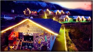 una casa illuminata di notte con luci sopra di Apple Retreat Resort a Kūfrī