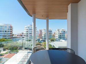 a balcony with a table and chairs and a view of buildings at LIV Mackenzie Beach Suites Larnaca in Larnaca