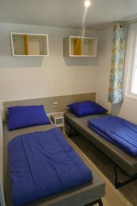 two beds in a room with blue pillows at VerandaChalet 6p centrally located in National Park, Swimming pool in Wateren