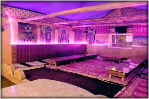 a room with purple lighting and a stage with tables at Apple Retreat Resort in Kūfrī