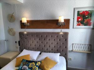 a bedroom with a bed with two lights on the wall at Logis HOTEL RESTAURANT La Régence in Cherbourg en Cotentin