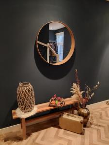 Cette chambre comprend un miroir et un banc en bois. dans l'établissement Dinie's Bed en Brood, à 's-Heerenbroek