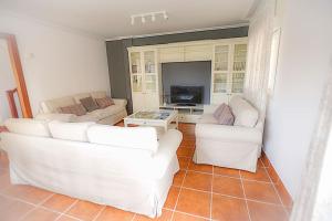 a living room with two white couches and a tv at Chalet junto a playa de Suances in Suances