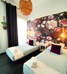 2 camas en una habitación con una pared floral en Hostal Mafer, en Santiago de Compostela