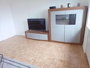 ein Wohnzimmer mit einem Flachbild-TV und Holzböden in der Unterkunft Vaste appartement cosy avec parking gratuit et espace de travail in Illkirch-Graffenstaden