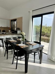 a dining room with a black table and a kitchen at Zeus Holiday Home in Pissouri