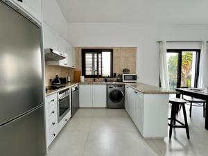 a white kitchen with a sink and a dishwasher at Zeus Holiday Home in Pissouri
