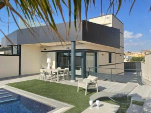 a house with a patio with a table and chairs at Luxury Villa with pool 1st line the sea in Torrevieja