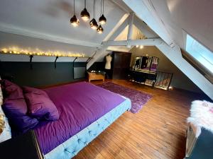 a bedroom with a large purple bed in a attic at Le Secret de Mélin in Mélin