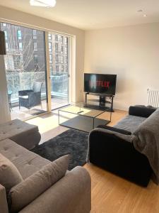 a living room with a couch and a flat screen tv at Luxury London Apartment - Steps To East Croydon Train Station in Croydon