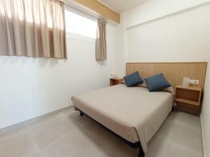 a bedroom with a bed with blue pillows and a window at Apartamento en El Prado in Cullera