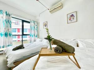 a white bedroom with two beds and a table at G1 Cozy 1-6Pax 3Q bed Sunway Medical Wifi Smart TV in Kampong Penaga