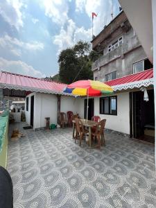 um pátio com uma mesa e guarda-chuva numa casa em Kheychun homestay em Darjeeling