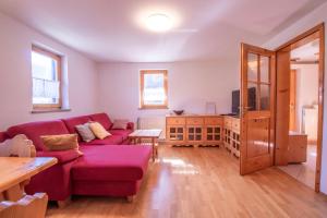 a living room with a red couch and a table at River Valley View House in Bohinjska Bistrica