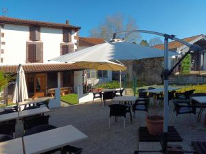 a patio with tables and chairs and an umbrella at Refuge d'étape Zuharpeta Randonneur Pèlerin in Saint-Jean-Pied-de-Port