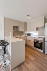 a large kitchen with white cabinets and a bar stool at Praia 58 Reñaca in Viña del Mar