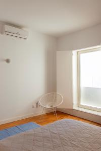 a white room with a chair and a window at Casa do Almirante in Tavira