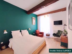 a bedroom with a large bed and a green wall at Le Prince in Marseillan