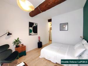 a bedroom with a white bed and a chair at Le Prince in Marseillan