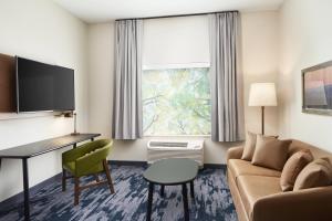 a hotel room with a couch and a desk and a window at Fairfield Inn & Suites Tampa Riverview in Riverview