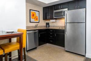 Residence Inn Tampa Downtown في تامبا: مطبخ مع دواليب سوداء وثلاجة حديد قابلة للصدأ