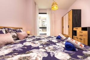 a bedroom with a large bed with a floral bedspread at Brand New Modern 1BR Apartment with Private Parking included in Plovdiv