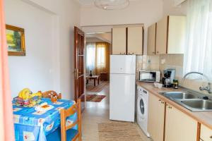 a kitchen with a table and a sink and a refrigerator at My Aegean Sea Apartment in Kos Town