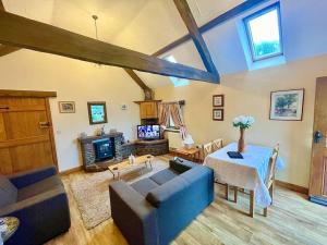 a living room with a blue couch and a tv at STONE BUILT BARN in a beautiful RURAL setting in Llangwm-isaf