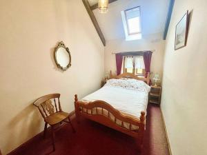 een slaapkamer met een bed, een spiegel en een stoel bij STONE BUILT BARN in a beautiful RURAL setting in Llangwm-isaf